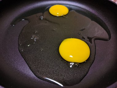 scrambled eggs in a pan. broken chicken eggs. Broken raw chicken egg in a frying pan. Cooking scrambled eggs. Cooking scrambled fried eggs, the egg broke together with the shell. Rush. Trouble happens.