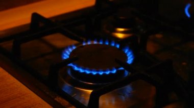 Gaz yanıkları. Gaz hobisi. Gaz açılır, mavi bir alev belirir. Siyah arka planda gaz sobası. Mutfak ocağı açık. En üstteki ocak, yemek pişirmek için mavi bir alevle tutuşturulur..