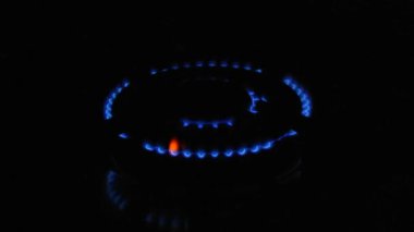 Gaz yanıkları. Gaz hobisi. Gaz açılır, mavi bir alev belirir. Siyah arka planda gaz sobası. Mutfak ocağı açık. En üstteki ocak, yemek pişirmek için mavi bir alevle tutuşturulur..