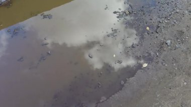 Gökyüzü bir su birikintisine yansıyor. Yoldaki büyük su birikintisi. Yağmur damlaları bir su birikintisine düşer, mavi gökyüzünü ve ağaçları yansıtır. Güneşin su birikintisindeki yansıması. Ağaç dallarının yansıması.