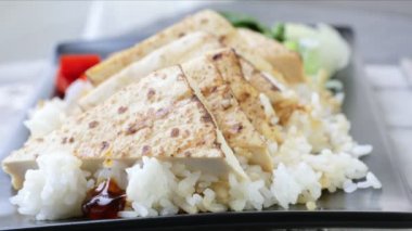 Kızarmış soya peynirinin üzerine teriyaki sosu dök pirinç yatağında otur.