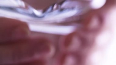 Hand holding measuring cup and pouring water, close up.