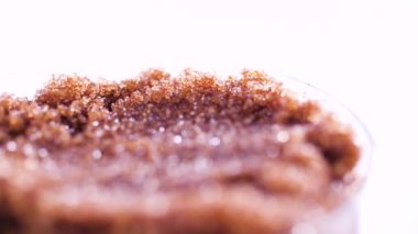 Close up of spoon scooping dark brown sugar from glass container