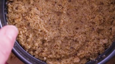 Graham cracker crust in small baking pan being picked up