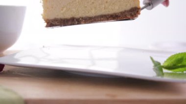 Placing slice of cheesecake on white plate