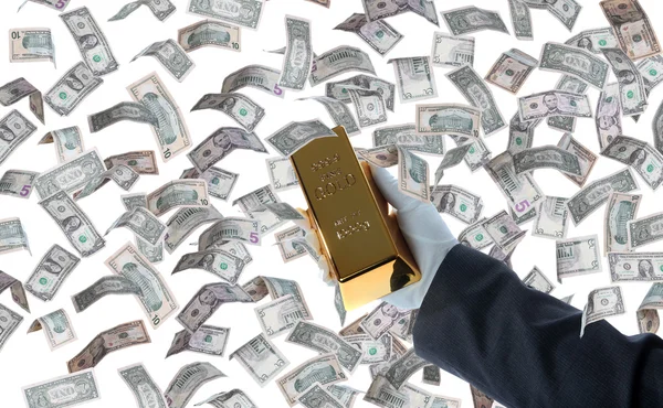 Bar of gold in hand and dollars — Stock Photo, Image