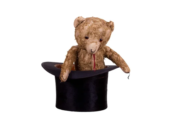 Old teddybear sitting in old black hat — Stock Photo, Image