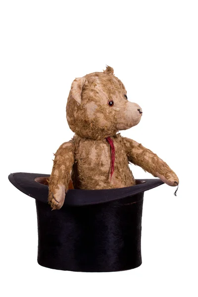 Old teddybear sitting in old black hat — Stock Photo, Image