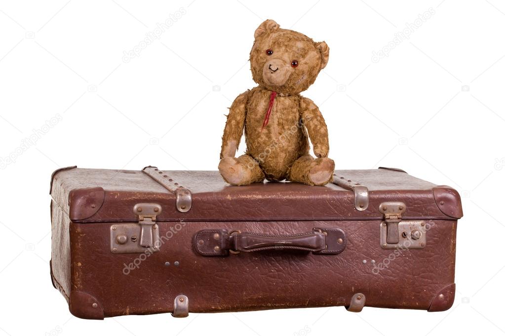 Old teddybear sitting on suitcase