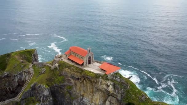 Ermita de San Juan de Gaztelugatxe-ról. Katolikus templom az Atlanti-óceán partján. Drónrepülés a sziklás sziget felett, Bakio, Spanyolország. — Stock videók