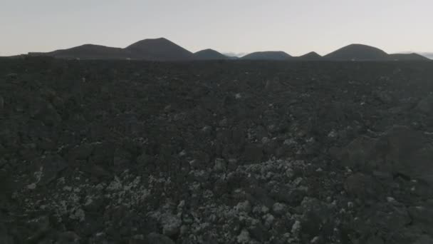 Vuelo con drones sobre los campos de lava en la isla de Lanzarote. Vista superior de la isla de Lanzarote. Vista aérea de campos de lava congelados negros en islas canarias. Campos de lava negra después de la explosión volcánica. — Vídeos de Stock