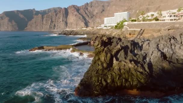 Vulkanisch zwembad in Los Gigantes, Tenerife. Rocky eiland in de Atlantische Oceaan. Stormachtige zee golven bedekken de rotsachtige kliffen. Top uitzicht op Tenerife eiland, Spanje. Stad op de rotsen van Tenerife eiland. — Stockvideo