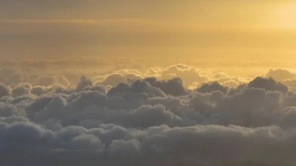 Kumuluswolken im Morgensonnenlicht. Weiße Wolken und oranger Himmel. — Stockfoto