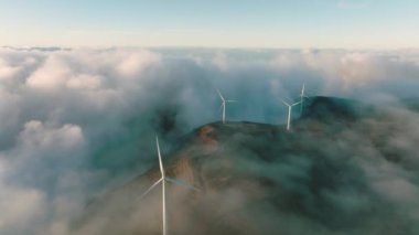 Wind turbines produce electricity in the mountains. Wind turbines hidden in the morning fog.