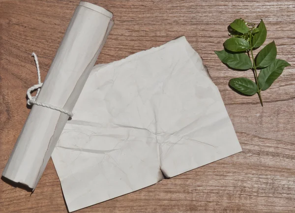 Antiguo rollo de papel arrugado en la mesa de madera con hoja verde para el fondo — Foto de Stock