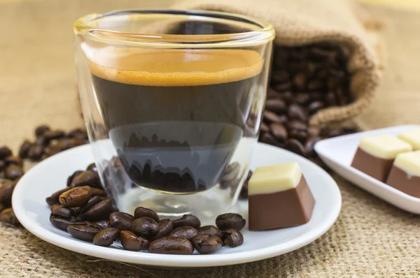 Frischer Espresso-Kaffee mit Crema und Pralinen auf Teller — Stockfoto