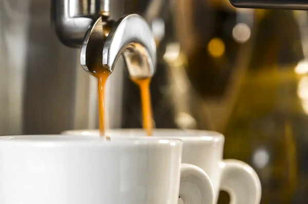 Golden espresso flowing into cups — Stock Photo, Image