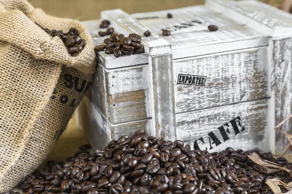 Wooden box from the supply of coffee next to burlap bag filled w — Stock Photo, Image