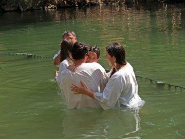 Israel Happy family after a baptism of the child in holy waters of the Jordan River clipart