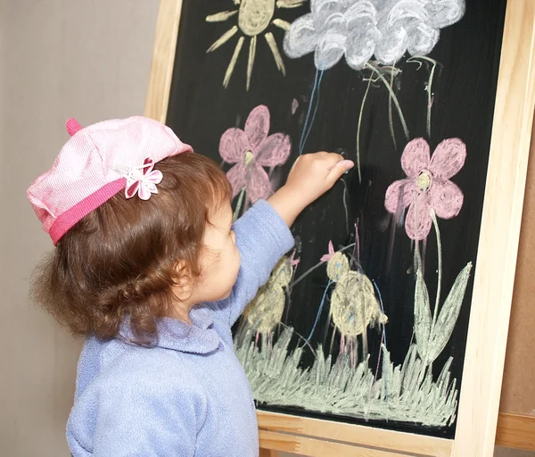 The little girl draws color pieces of chalk on an easel — Stock Photo, Image