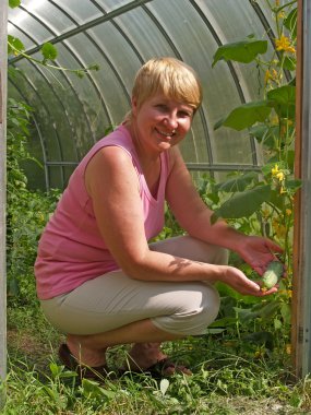 The woman holds a cucumber