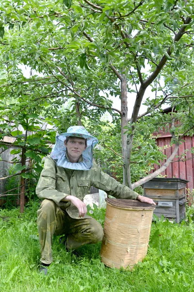 The young beekeeper from swarms to it on an apiary — Stock Photo, Image