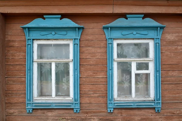 Zwei Fenster mit blauen geschnitzten Verkleidungsbrettern — Stockfoto