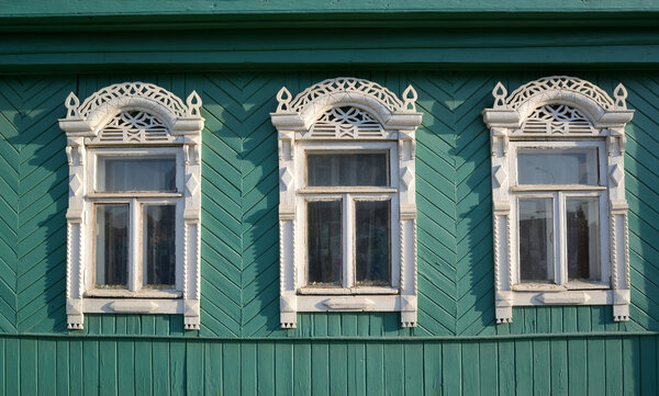 Three windows with white carved platbands