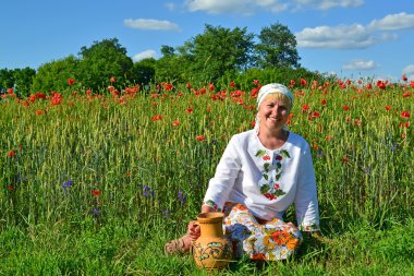 haşhaş bir alanda bir sürahi ile kırsal kadın oturur
