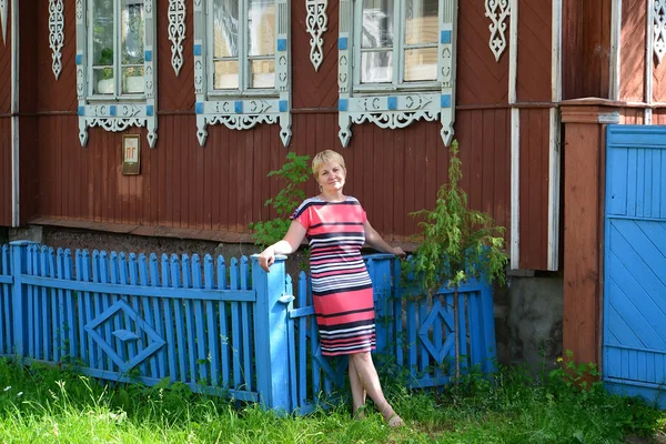 A mulher fica perto da casa de madeira com bandas de plataforma esculpidas — Fotografia de Stock