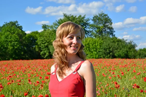 The young woman smiles in a poppy field — Stock Photo, Image