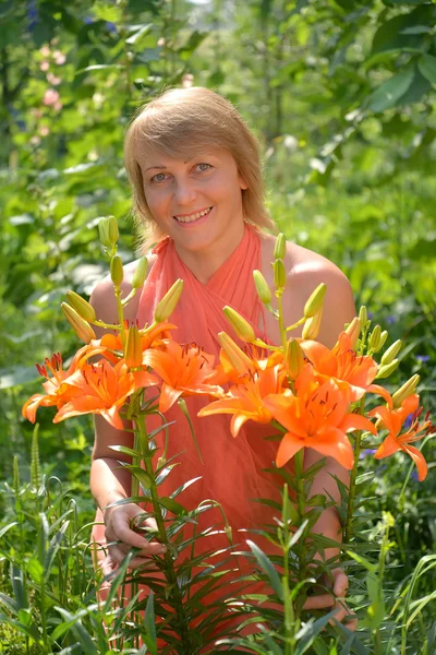 Retrato de la mujer de mediana edad con lirios anaranjados — Foto de Stock