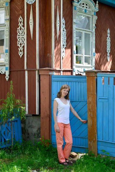 A jovem abre um portão para a casa de madeira com pla esculpida — Fotografia de Stock
