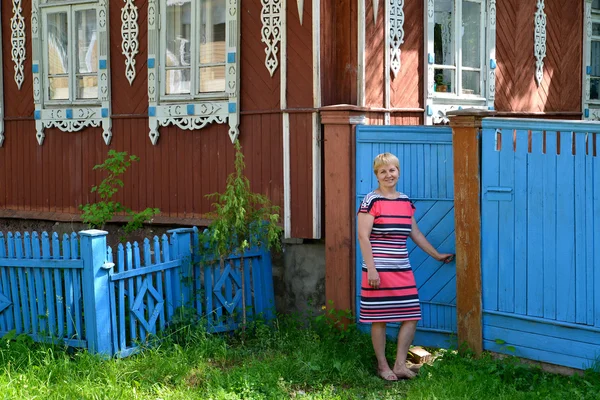 A mulher abre um portão a uma jarda da casa de madeira — Fotografia de Stock