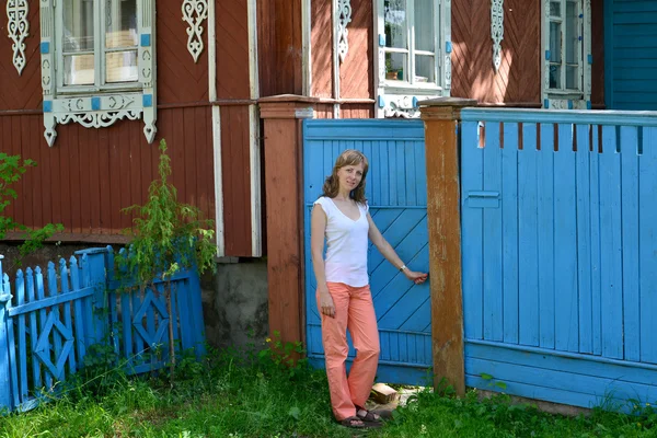 La giovane apre un cancello alla casa in legno con pla intagliato — Foto Stock