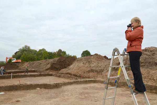 Die Frau fotografiert archäologische Ausgrabungen, stehend auf einem l — Stok fotoğraf