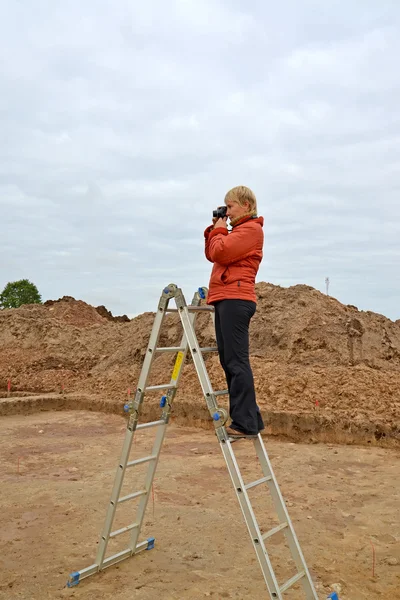 A mulher fotografa escavações arqueológicas, de pé sobre um l — Fotografia de Stock