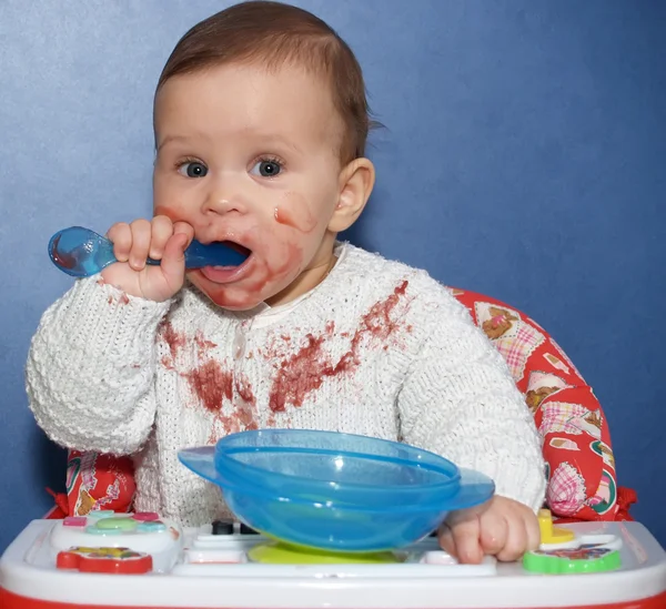 The little girl independently eats with a spoon — Stock Photo, Image