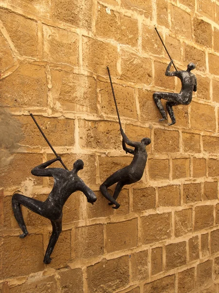 Figuren der Menschen, die an einer Wand klettern. yaffo, israel — Stockfoto