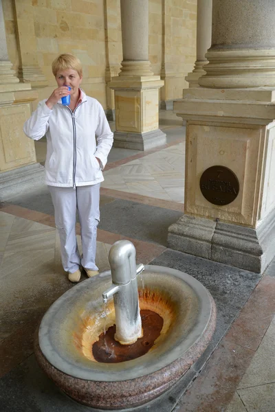 La mujer bebe agua de una fuente mineral en Karlovy Vary (fo —  Fotos de Stock