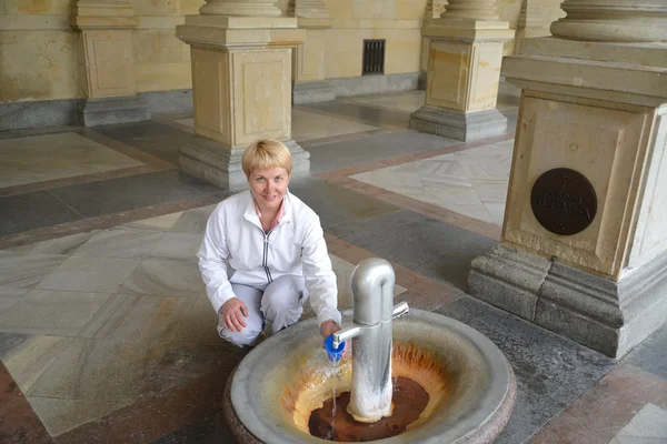 The woman pours water from a mineral source in Karlovy Vary, the — Stock Photo, Image