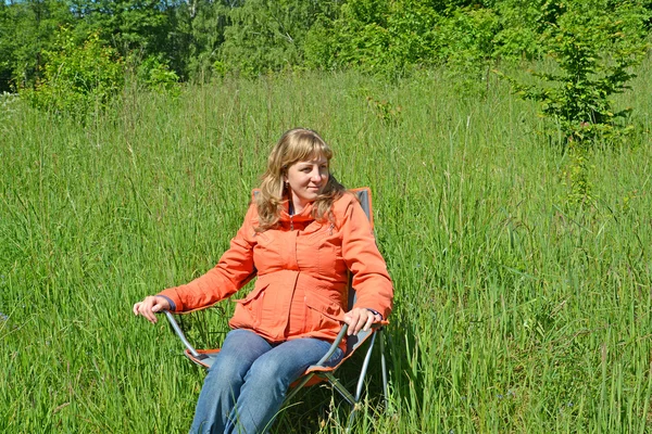 The pregnant woman sits in a folding chair among a green grass — Stock Photo, Image