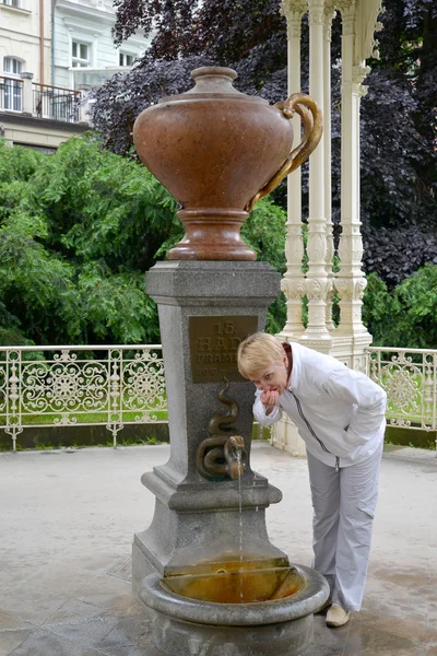 A mulher bebe água de uma fonte mineral "Cobra" em Karlovy — Fotografia de Stock