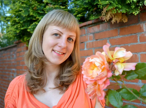 Die fröhliche junge Frau mit Rosen — Stockfoto