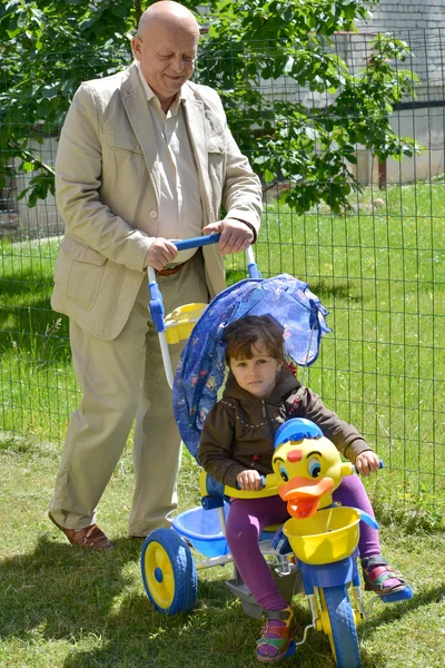 El abuelo monta a la nieta en la bicicleta de los niños —  Fotos de Stock