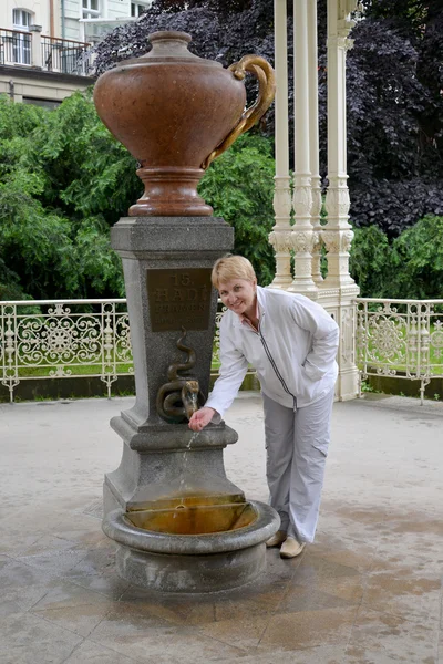 Žena pije vodu z minerální zdroje "Had" v Karlových — Stock fotografie