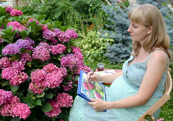 A fiatal terhes női előadó felhívja a víz színe fest egy virág — Stock Fotó