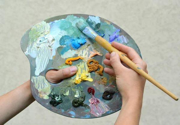 Руки художника держат палитру красок и кисти — стоковое фото