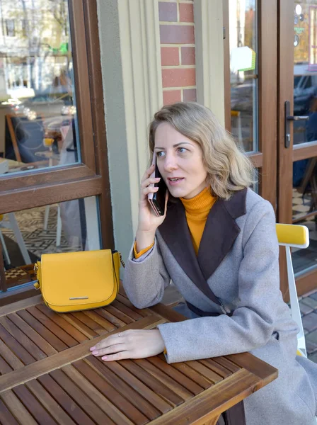 Kobieta Rozmawiająca Przez Telefon Siedząca Przy Stoliku Ulicznej Kawiarni — Zdjęcie stockowe