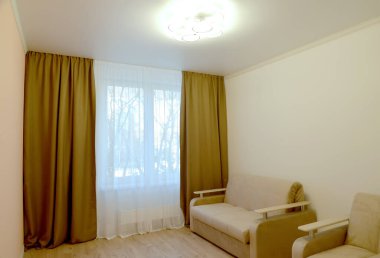 Oturma odasının içinde tavan lambası ve yumuşak mobilyaları olan bir parça.